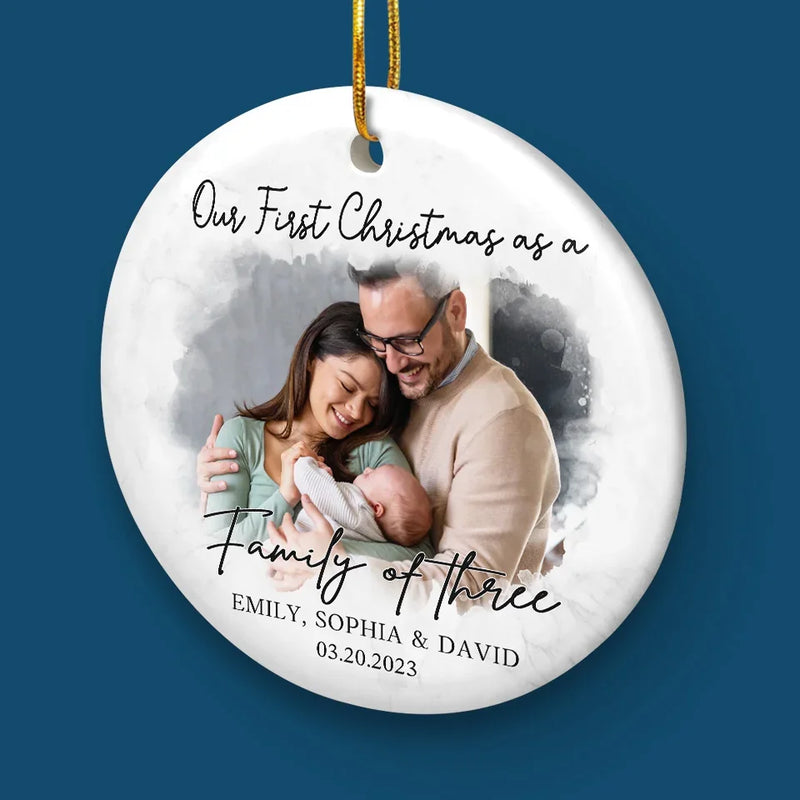 Custom Photo Our First Christmas As A Family Of Three - Couple Personalized Custom Ornament - Ceramic Round Shaped - Christmas Gift For Husband Wife, Anniversary, First Christmas